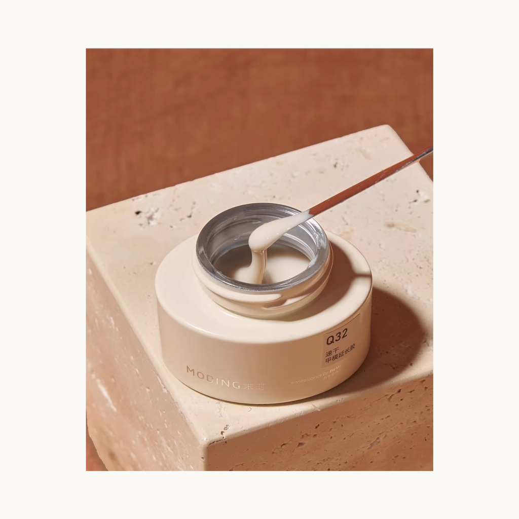 Close-up shot of MODING Q32 builder gel showing creamy texture lifted by a metal spatula.