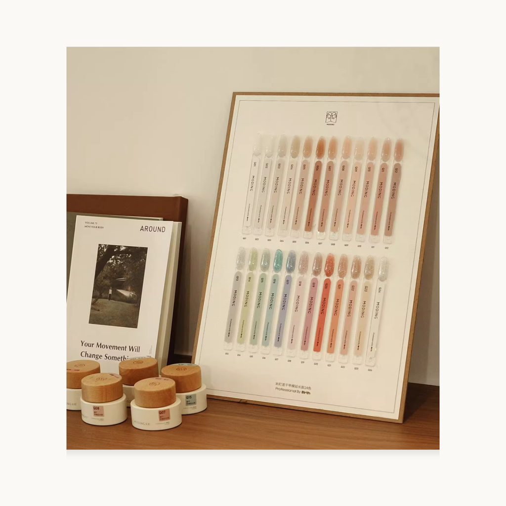 Swatch board display of MODING colored extension gel shades with gel jars arranged beside books for a professional nail studio presentation.