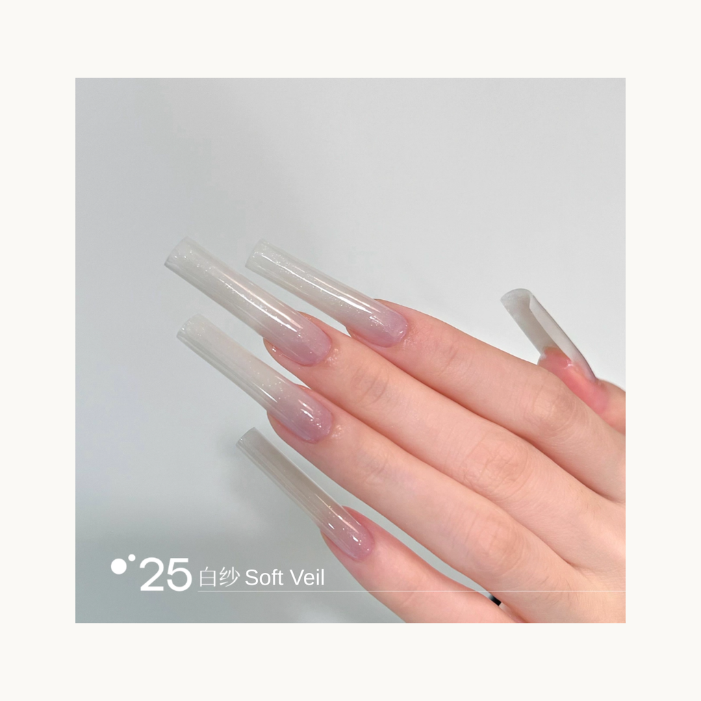 Long coffin-shaped nails painted in shade Q25 Soft Veil, a sheer milky-white gradient with a translucent glossy finish.