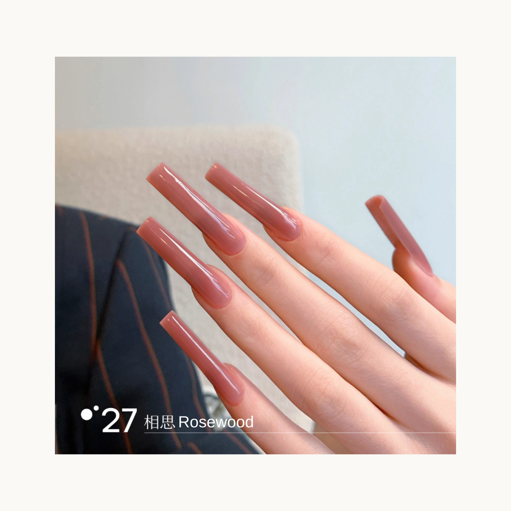 Long coffin-shaped nails painted in shade Q27 Rosewood, a warm rose-nude gradient with a glossy finish.