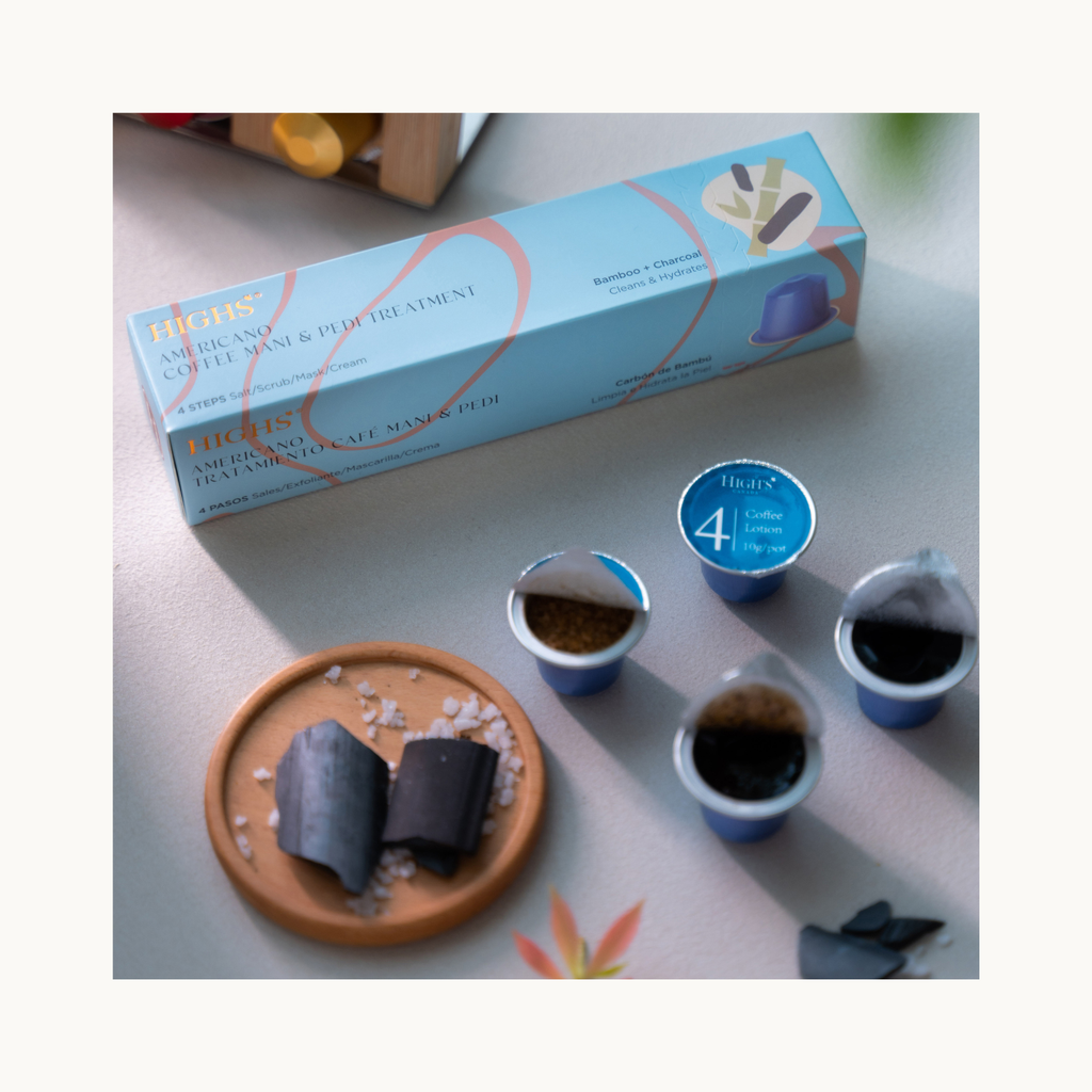 Flatlay of HIGHS Americano Coffee hand and foot treatment with charcoal soak scrub mask lotion cups and bamboo charcoal details