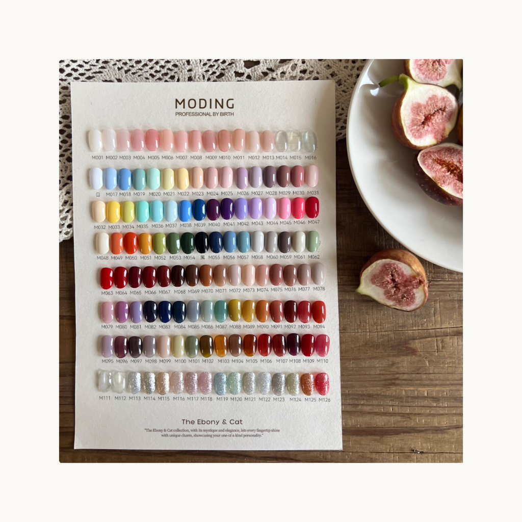 MODING 128 Colors Gel Polish color chart flatlay on wooden table with figs, showing full shade range