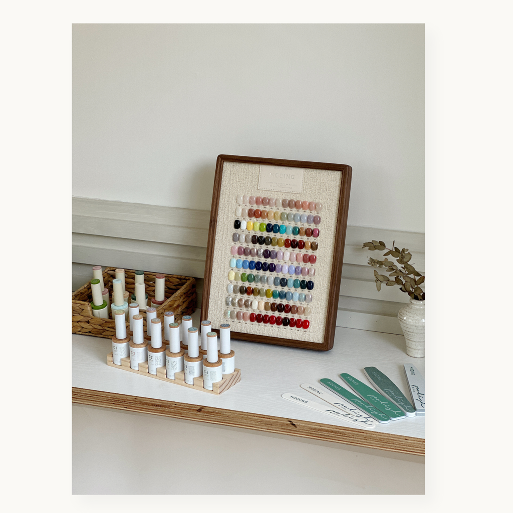 MODING 130-color full set with bottle gels arranged on desktop beside a framed swatch display.