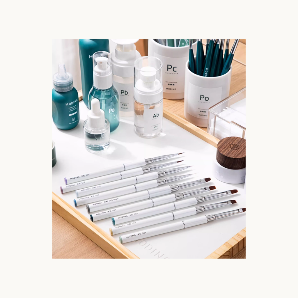 MODING nail art brushes and manicure tools arranged on a clean studio desktop