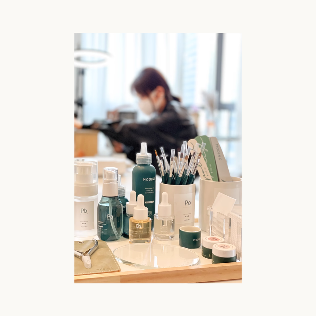 MODING nail salon workstation setup showcasing pump bottles, brushes, liquids, and manicure tools