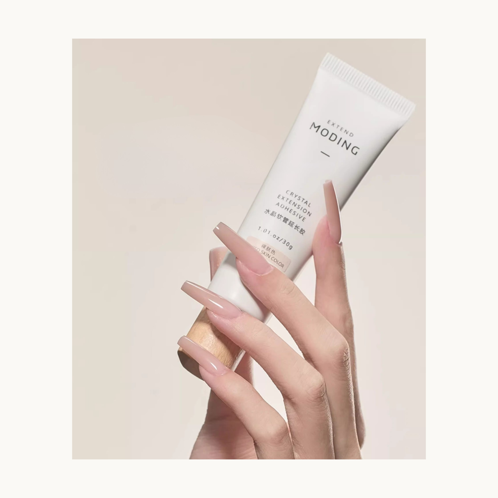 Hand holding MODING poly gel in nude color with freshly extended nude nails.