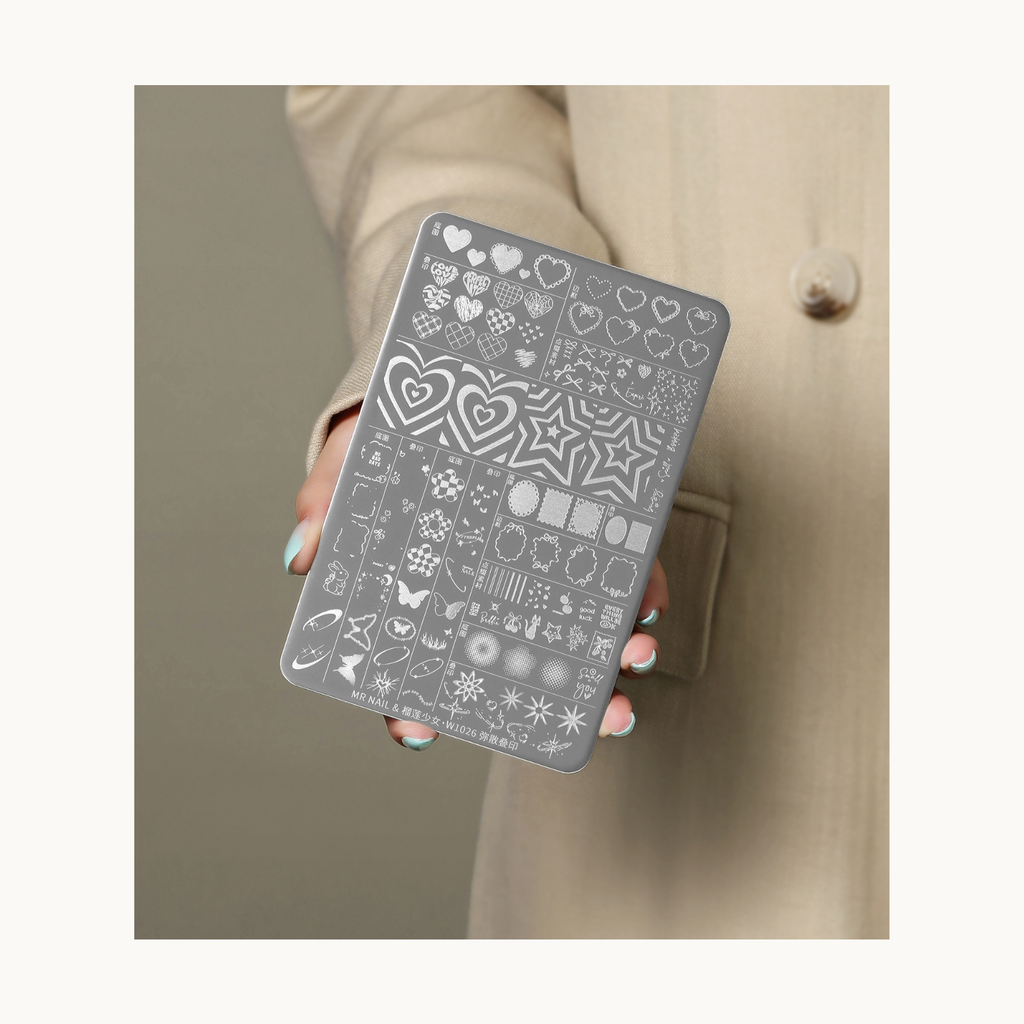 Hand-held display of MR NAIL W1026 mixed hearts and stars nail stamping plate, showing size reference and engraving clarity.