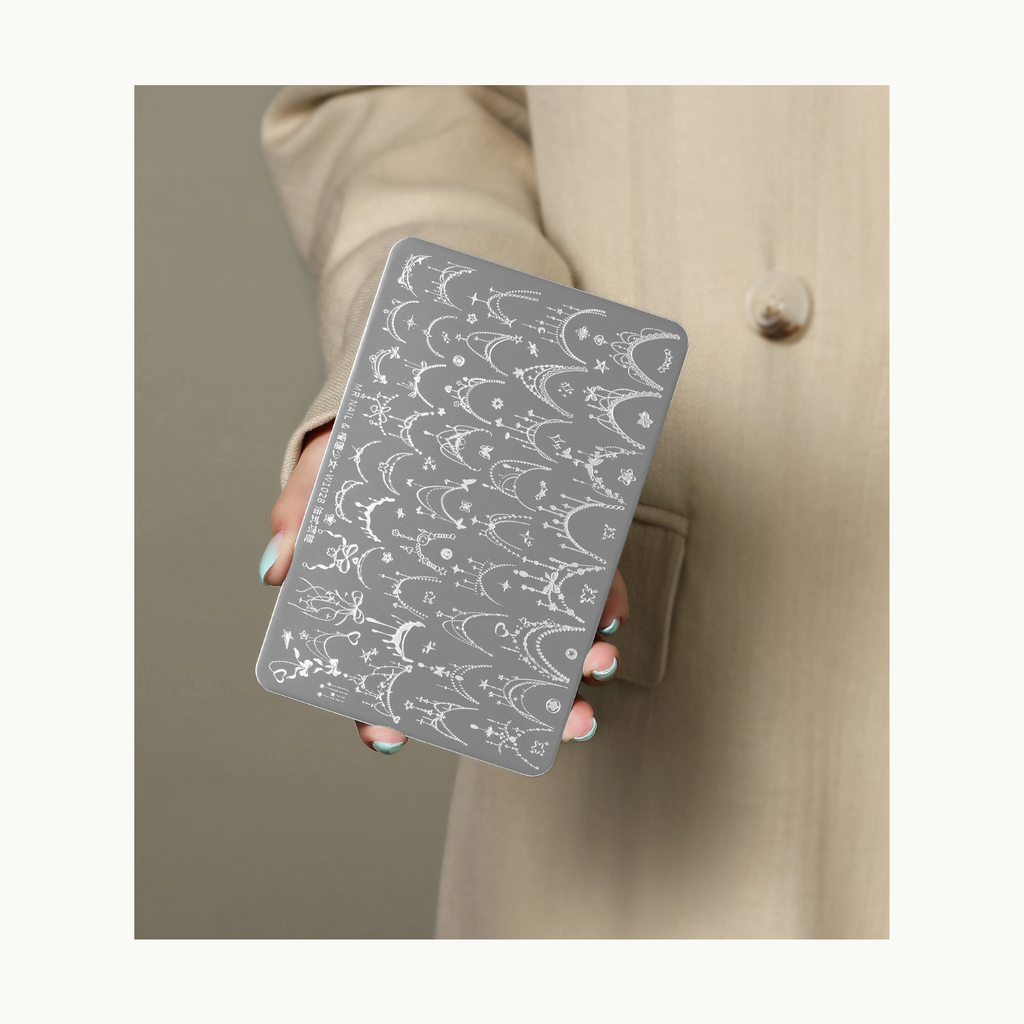 Hand holding MR NAIL W1028 Gothic Tiara stamping plate showing crown and elegant jewelry nail art designs