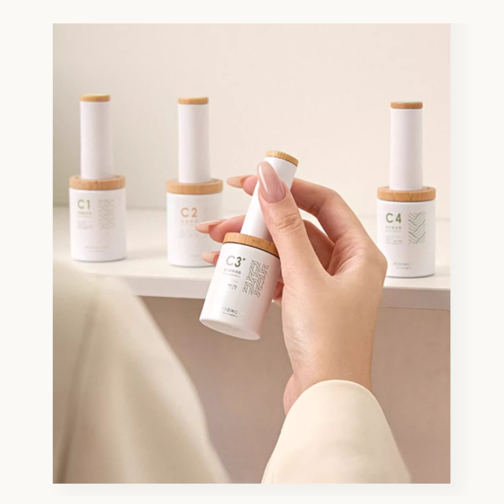 Person hand holding functioanl nail gel of a white bottle with a wooden cap, surrounded by similar bottles on a shelf.