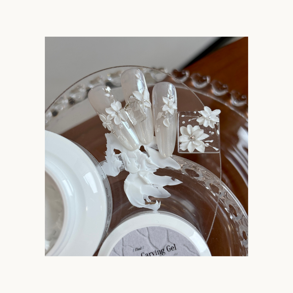 Long clear nails decorated with delicate 3D white flowers sculpted using carving gel.