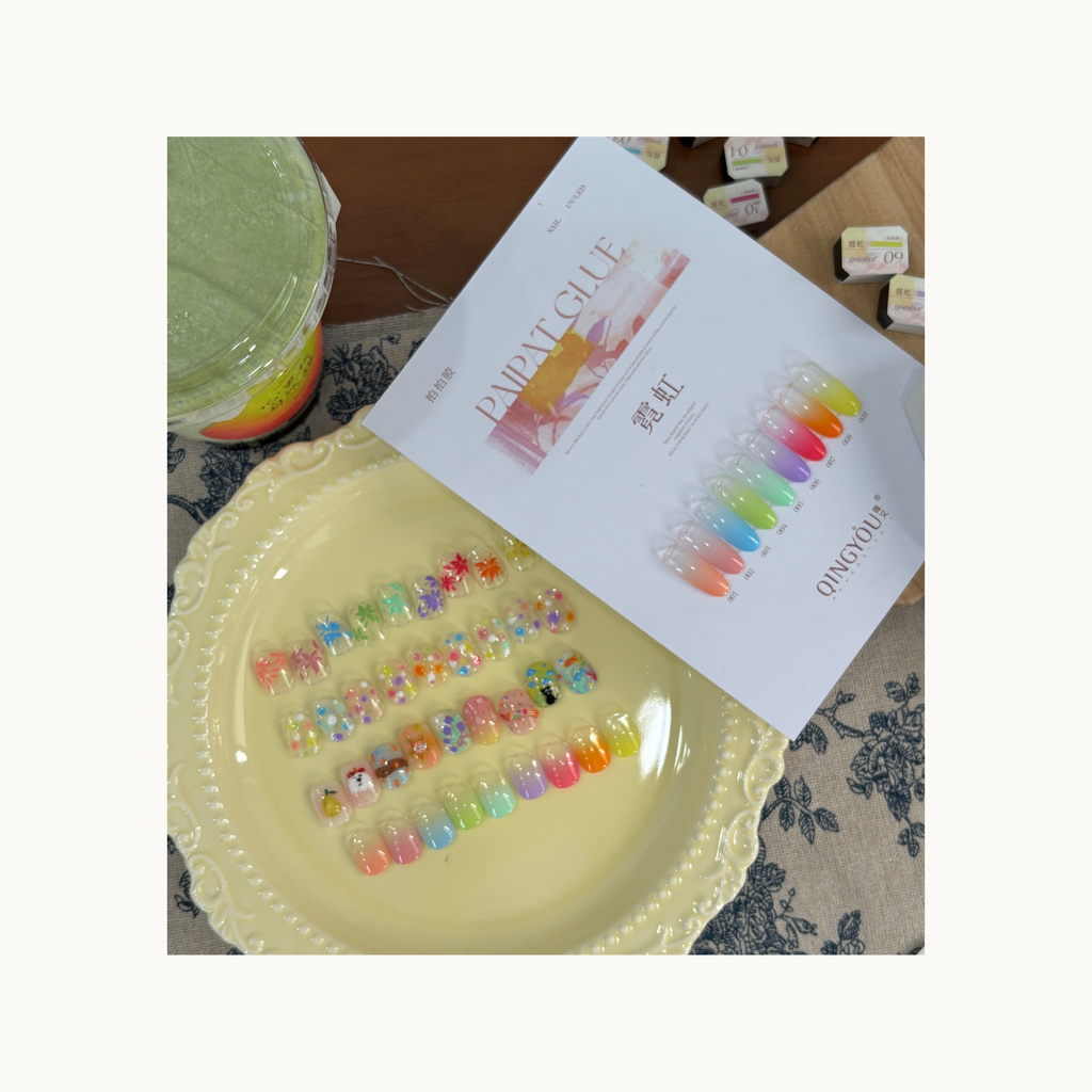 QINGYOU neon paint gel set displayed with rainbow gradient nail samples and decorative nail designs on a plate.
