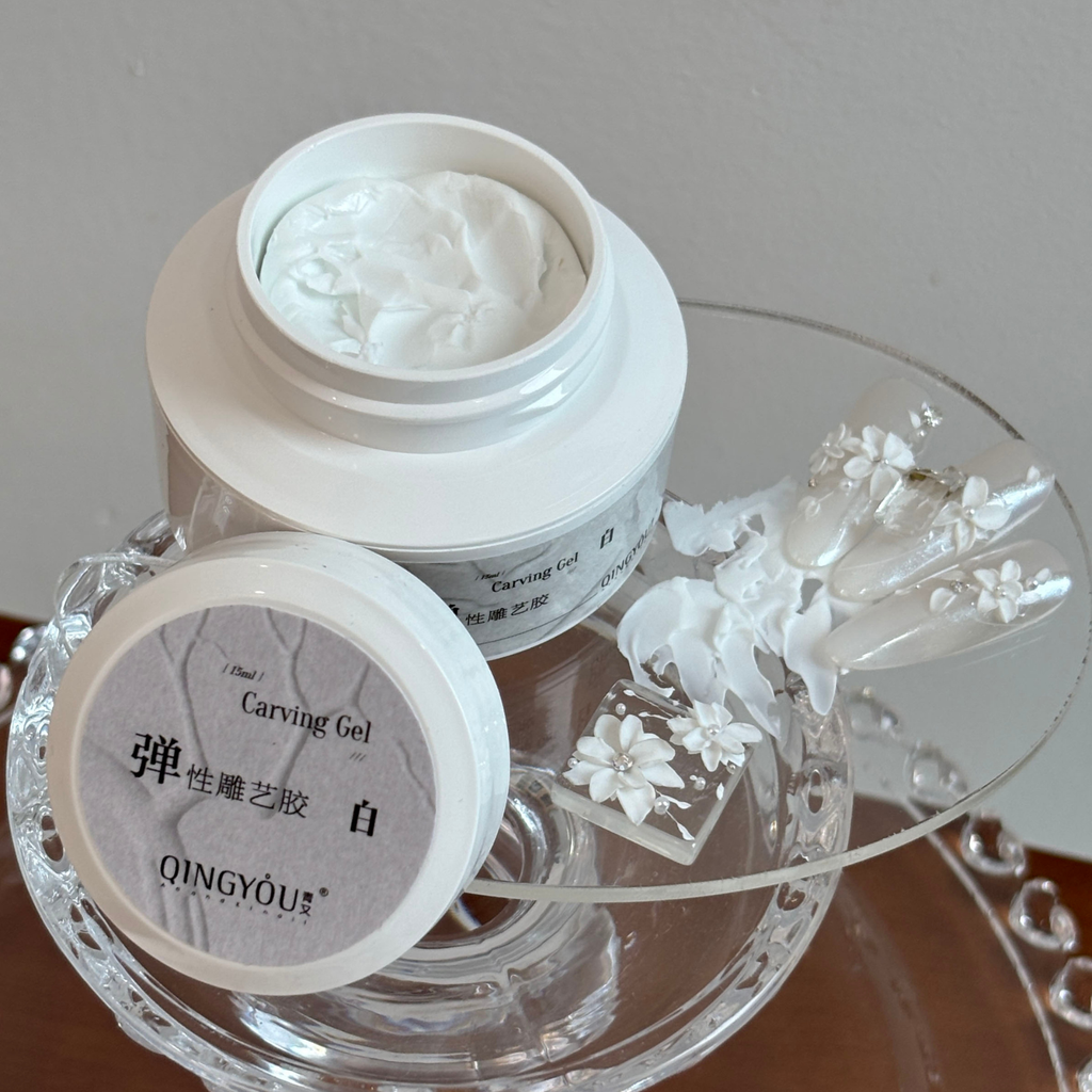 White elastic carving gel creating 3D floral nail art with sculpted petals on a clear base.