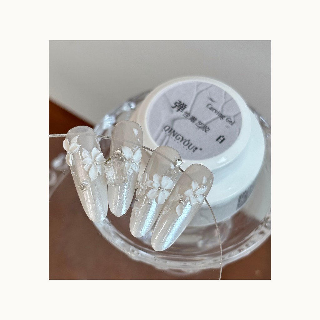 Layered 3D floral nail details created using white elastic carving gel for textured designs.