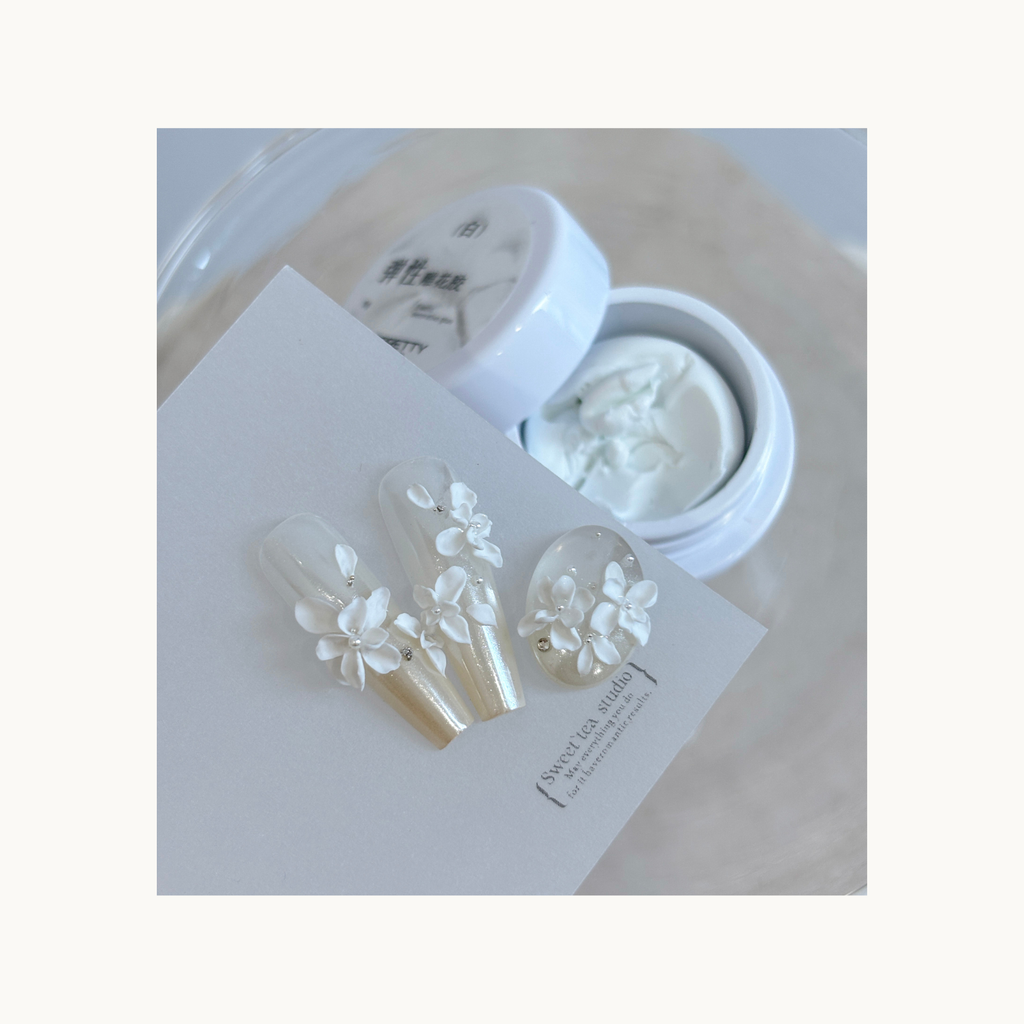 3D white carved flowers made using QINGYOU elastic carving gel on pearly nail tips.