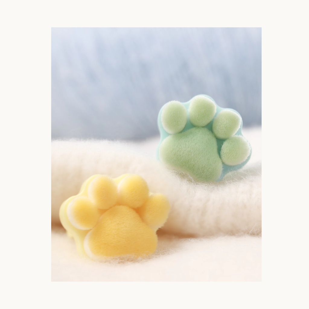 Pastel yellow and mint green Meow Paw Brushes displayed on fluffy background
